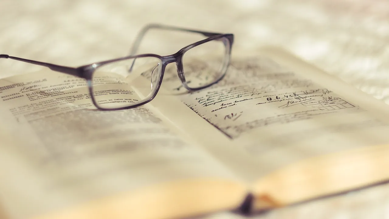 Une paire de lunettes posée sur un registre couvert d’une écriture ancienne